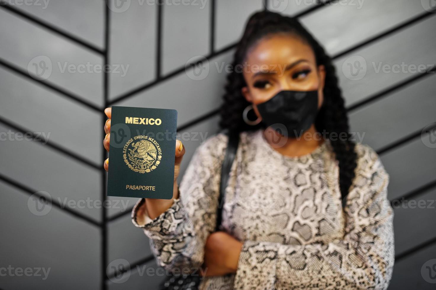 afroamerikanerin mit schwarzer gesichtsmaske zeigt mexiko-pass in der hand. coronavirus im amerikanischen land, grenzschließung und quarantäne, virusausbruchskonzept. foto