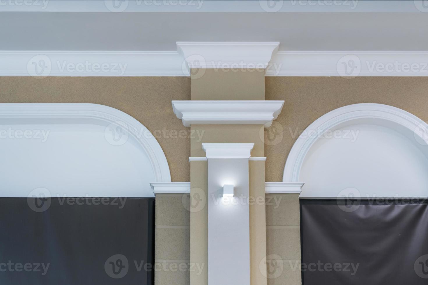 Detail der Eckdecke mit komplizierter Zierleiste auf Säule mit Spotlicht foto