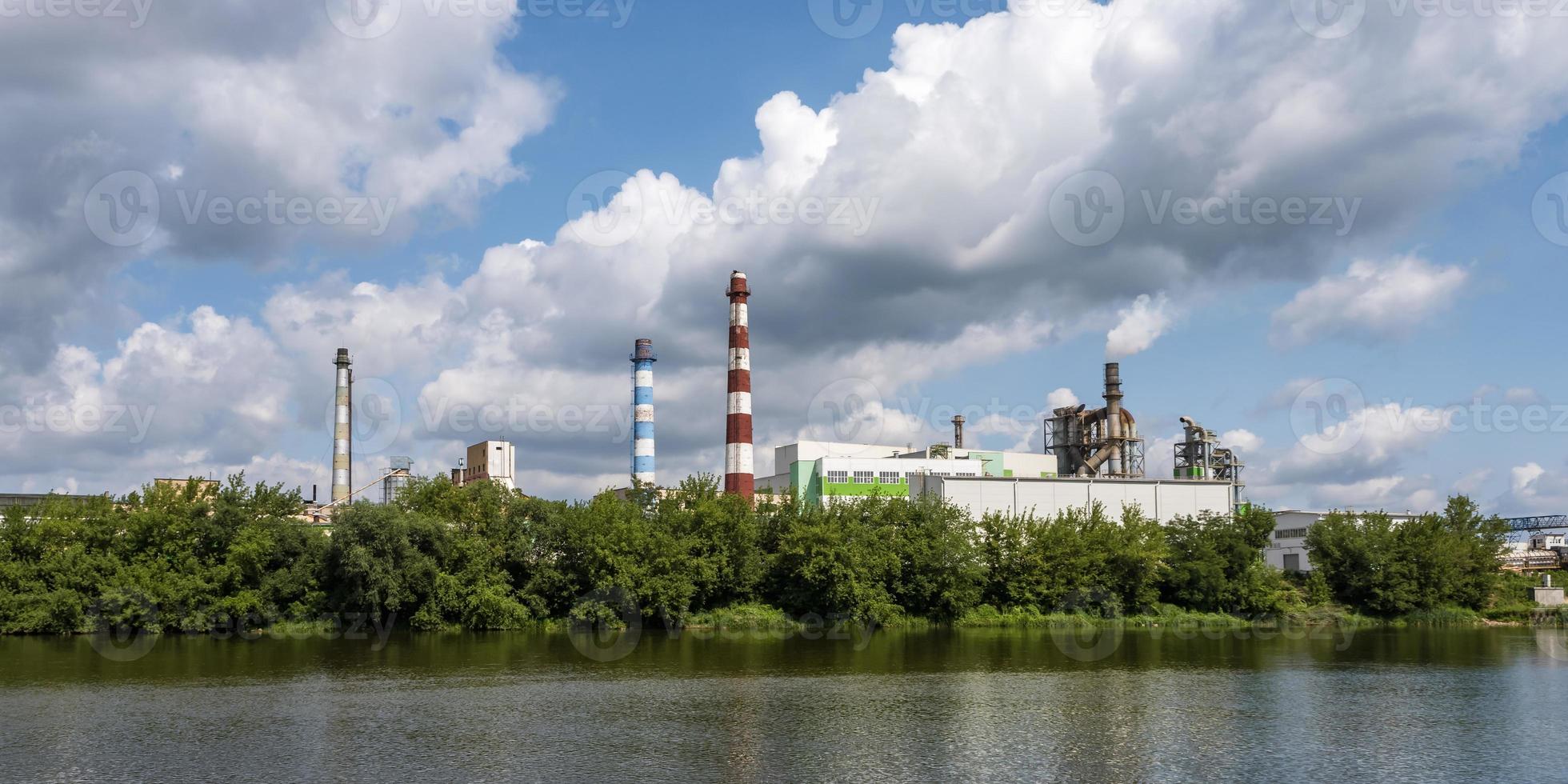 Rohre des Sägewerks des Holzbearbeitungsunternehmens in der Nähe des Flusses. Luftverschmutzungskonzept. Industrielandschaft Umweltverschmutzung Abfall von Wärmekraftwerken foto