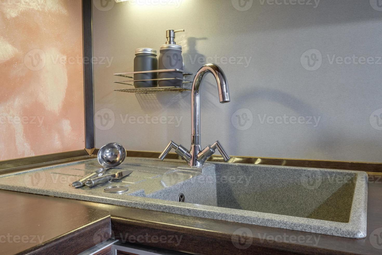 Seifen- und Shampoospender in der Nähe von keramischem Wasserhahn mit Wasserhahn in teurer Küche foto
