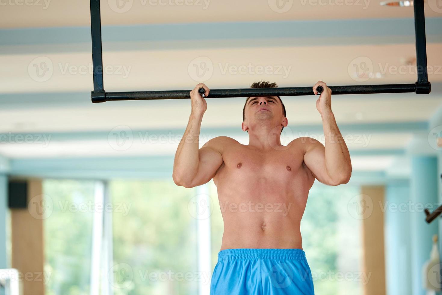 hübscher junger Mann, der im Fitnessstudio trainiert foto