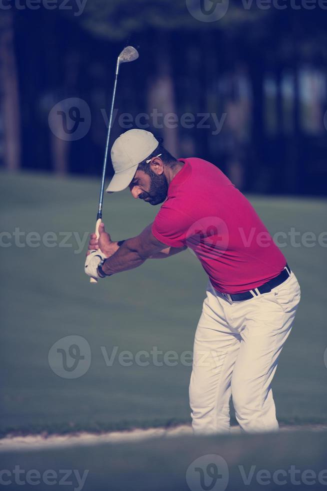 Golfspieler, der einen Sandbunkerschlag schlägt foto