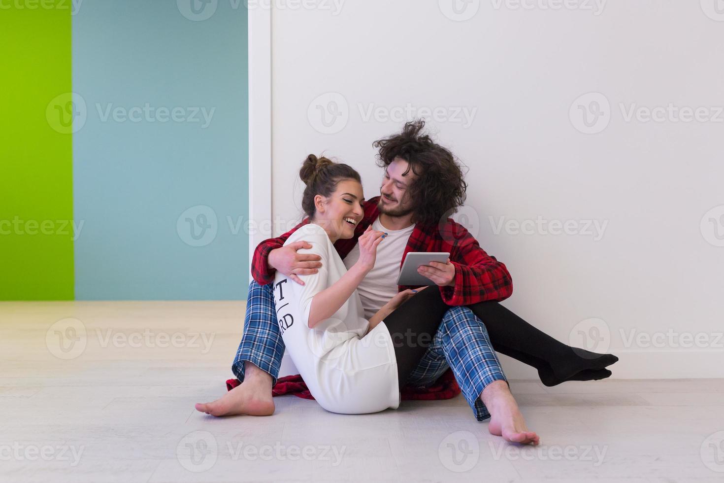 junges Paar mit digitalem Tablet auf dem Boden foto