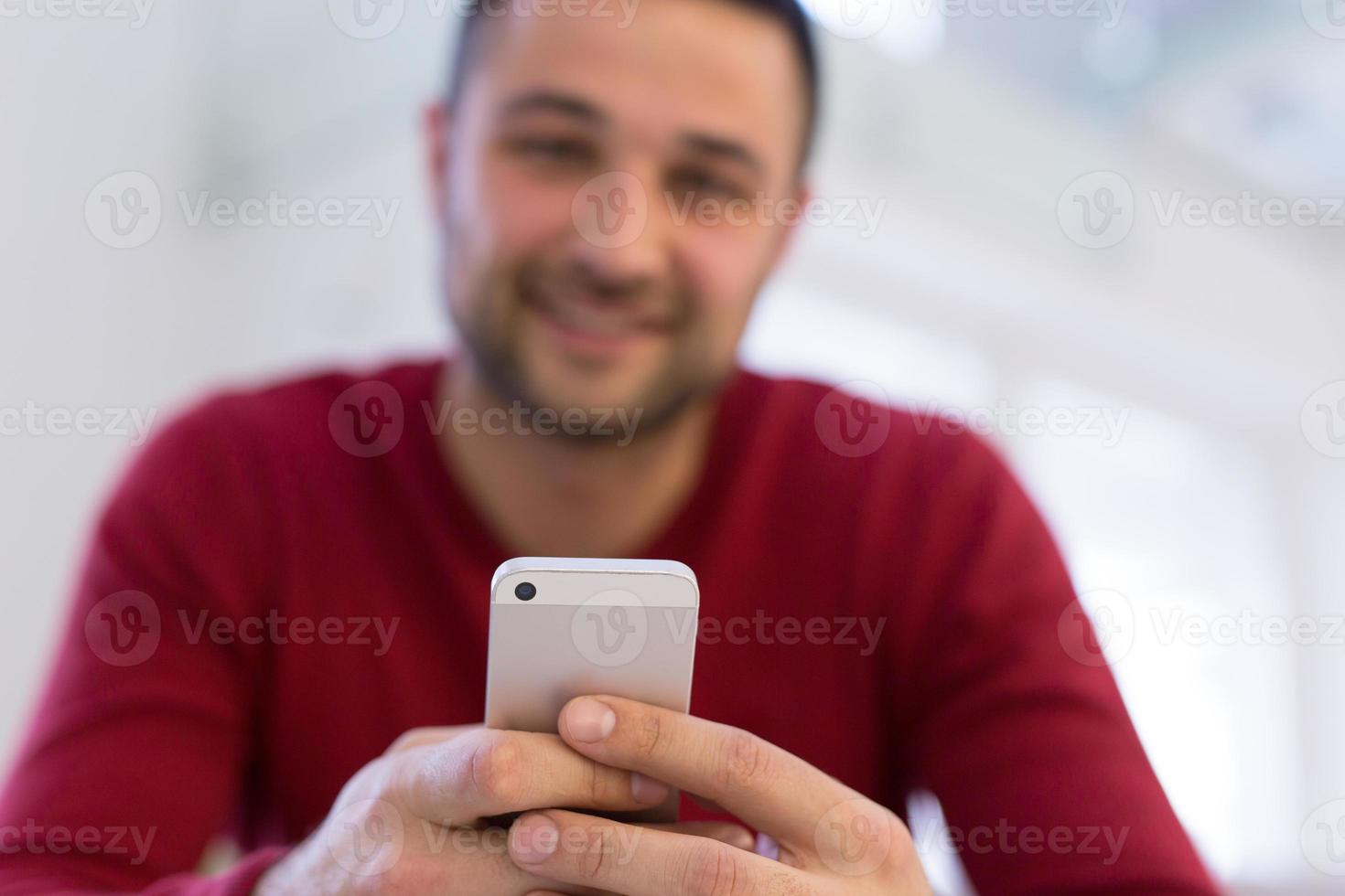 junger mann, der zu hause ein handy benutzt foto