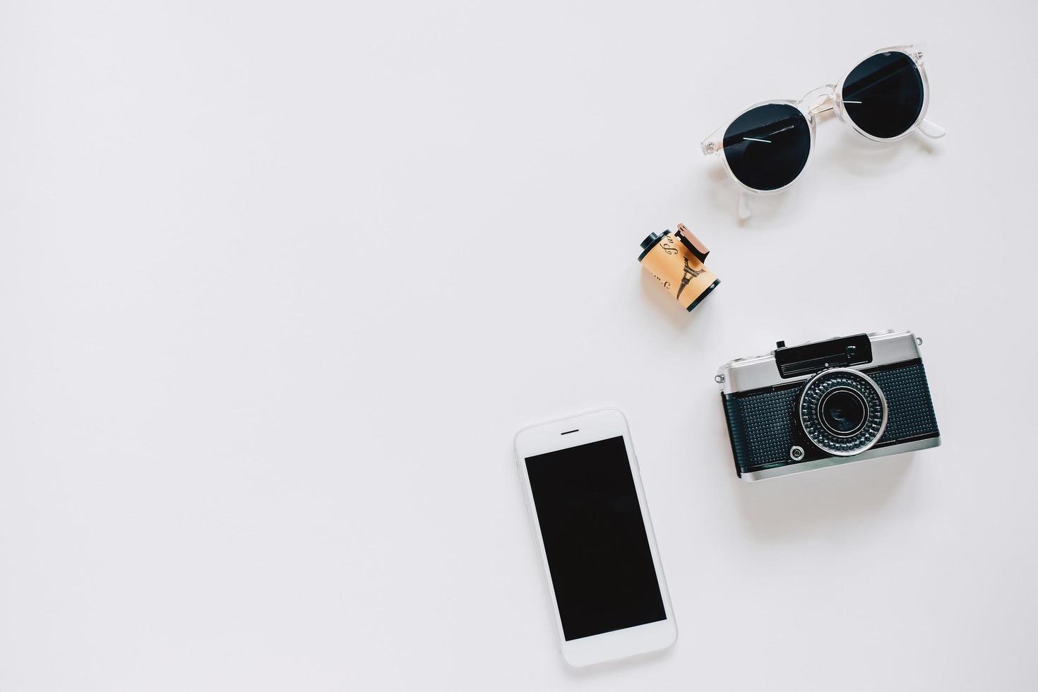 kreativer flacher lagstil mit filmkamera, sonnenbrille und smartphone auf weißem hintergrund mit kopienraum foto