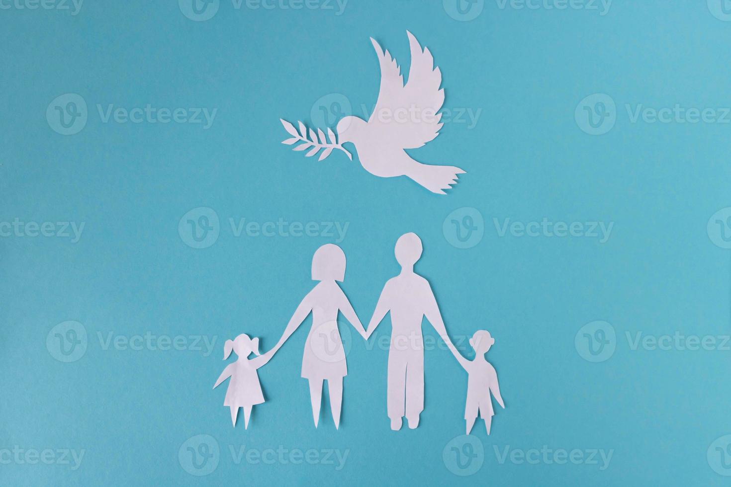 eine Papierfamilie auf blauem Grund, darüber schwebt eine Friedenstaube. das konzept des familientages, des bruder- und schwestertags, des menschenrechtstages, des weltfriedenstages foto