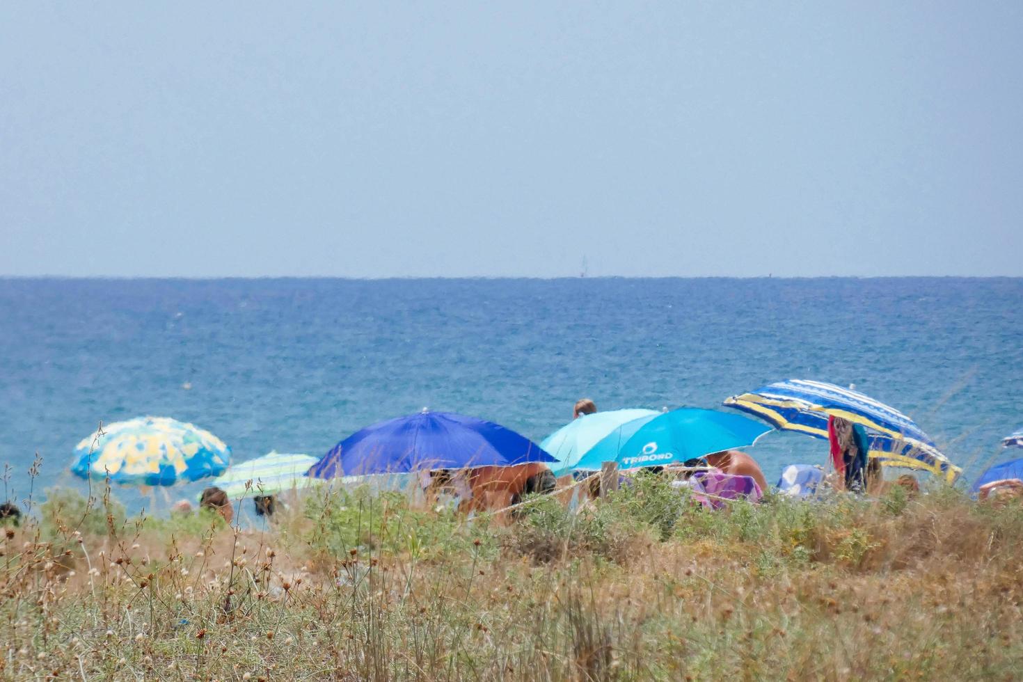 menschen sonnen sich unter sonnenschirmen am strand foto