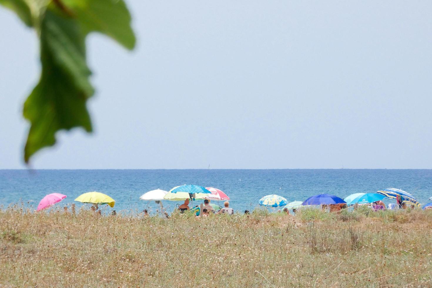 menschen sonnen sich unter sonnenschirmen am strand foto