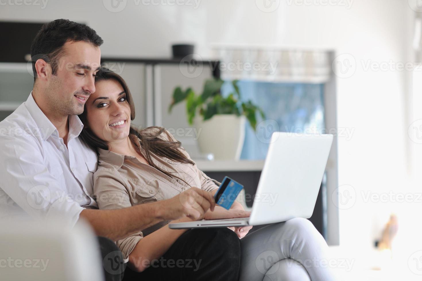 Fröhliches Paar entspannen und arbeiten am Laptop im modernen Zuhause foto