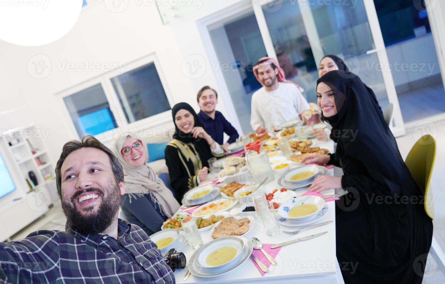 muslimische familie beim iftar-abendessen, das fotos mit dem handy macht