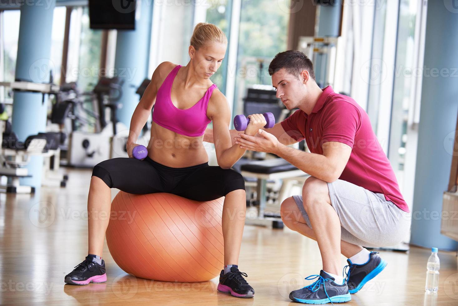 junge sportliche frau mit trainer übung gewichte heben foto