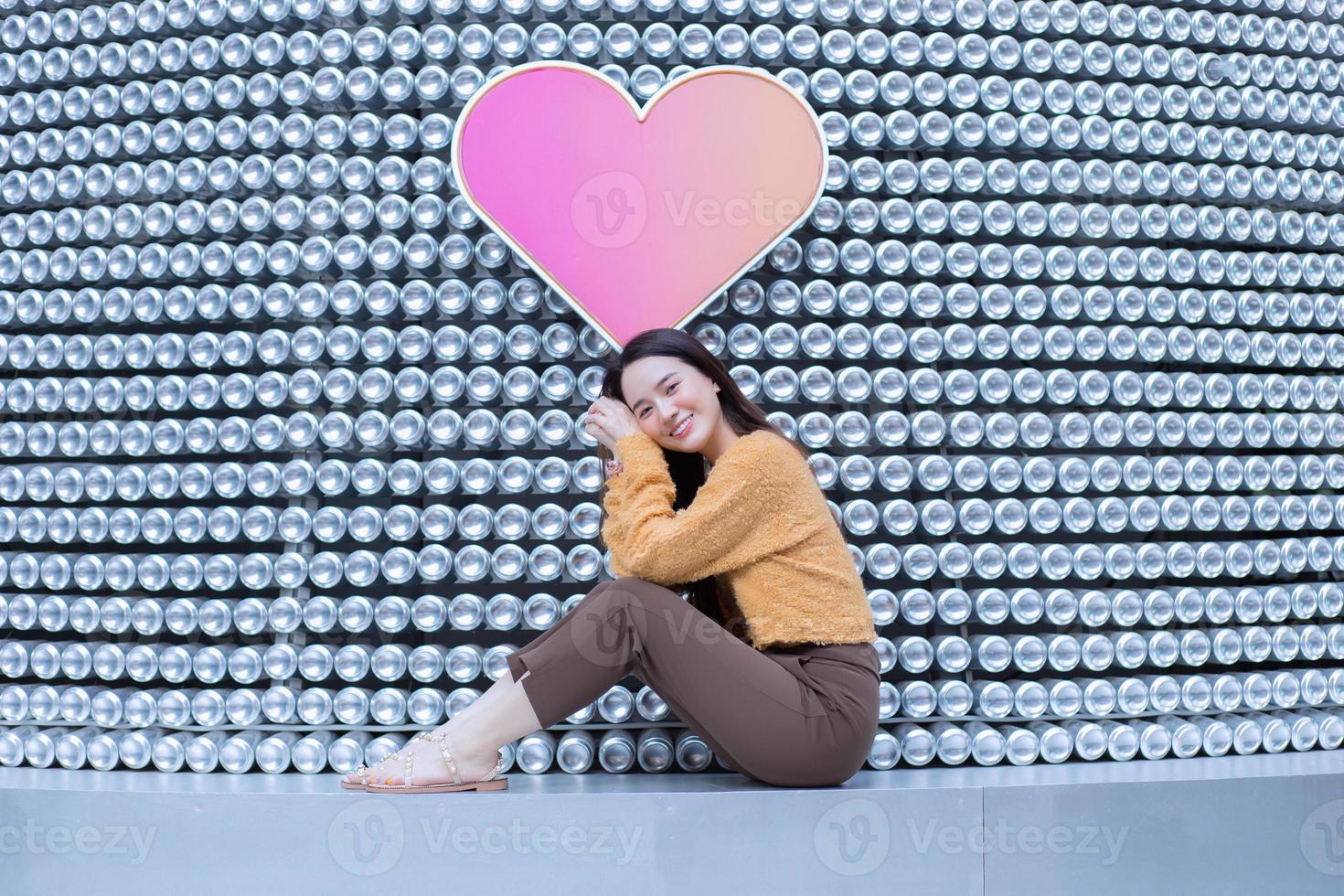 schöne asiatische frau im schwarzen langen haar trägt gelben mantel und frisches lächeln im valentinsthema. foto