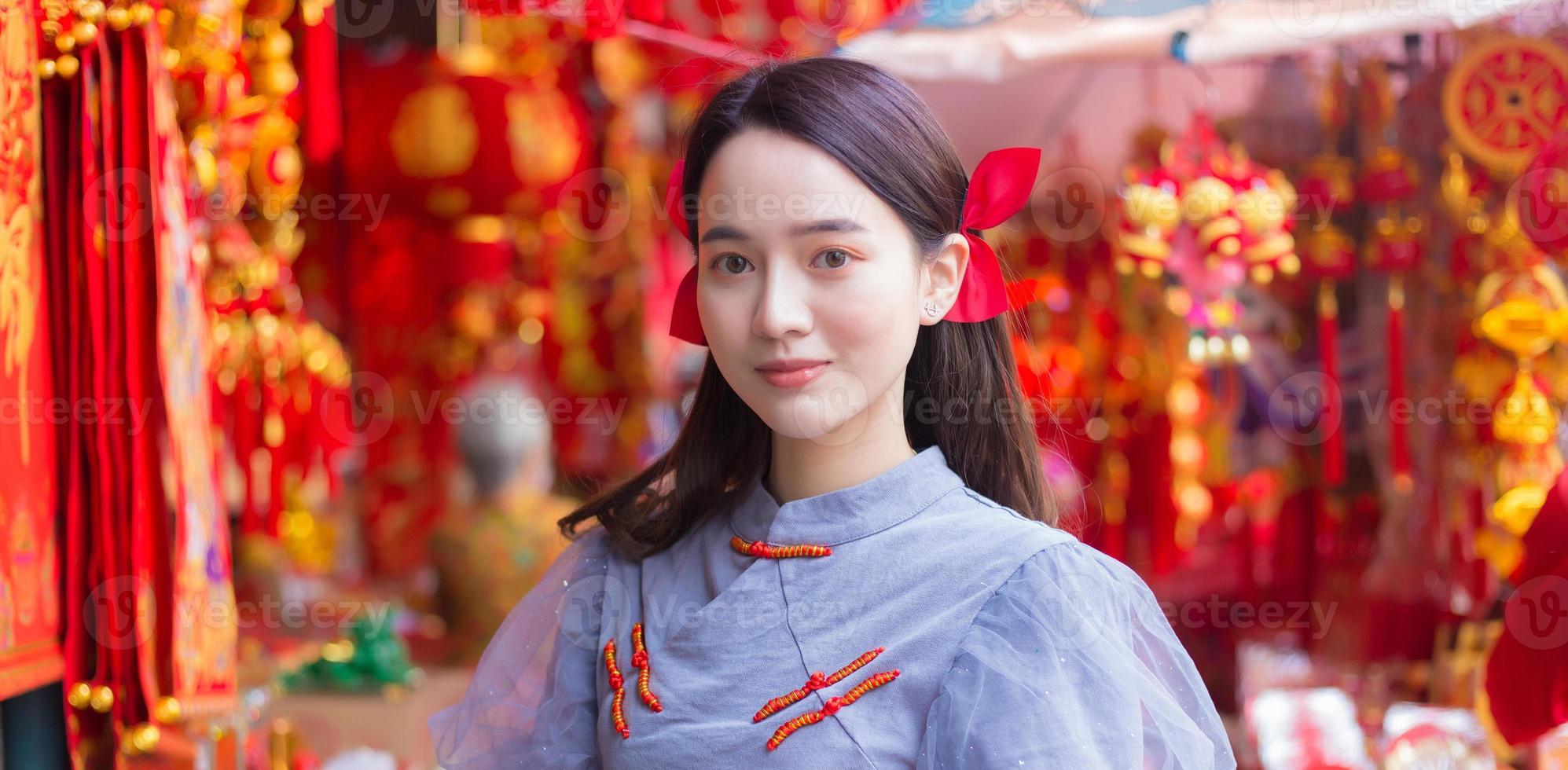 asiatische schöne frau im langen haar trägt ein graues chinesisches kleid mit chinesischem neujahrsthema. foto