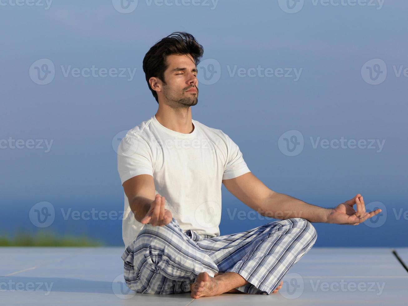 junger Mann, der Yoga praktiziert foto