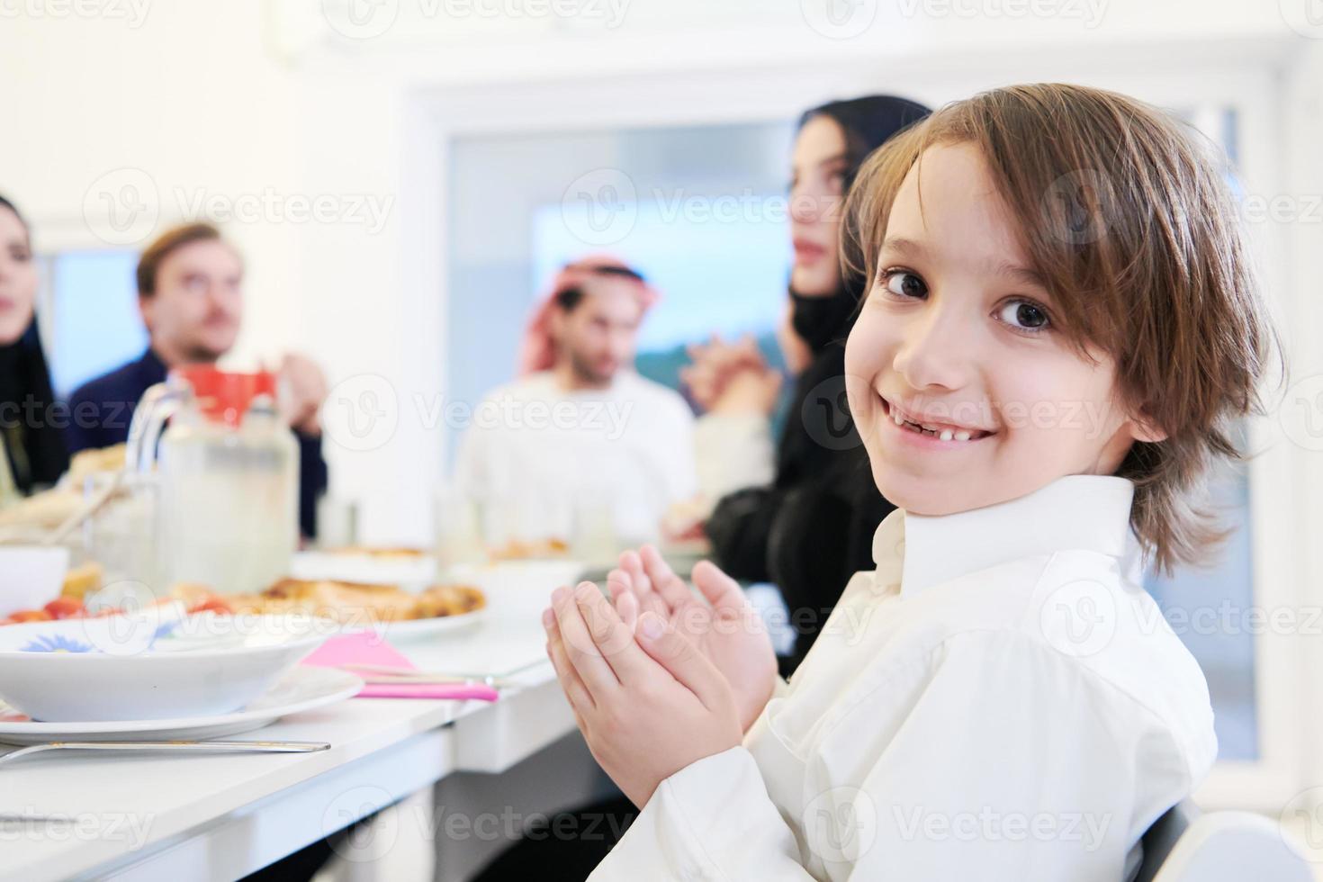 kleiner muslimischer junge, der vor dem iftar-abendessen mit der familie betet foto