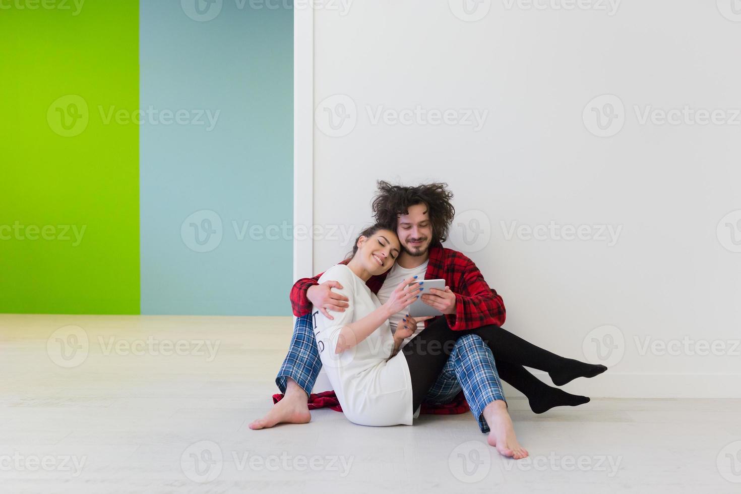 junges Paar mit digitalem Tablet auf dem Boden foto