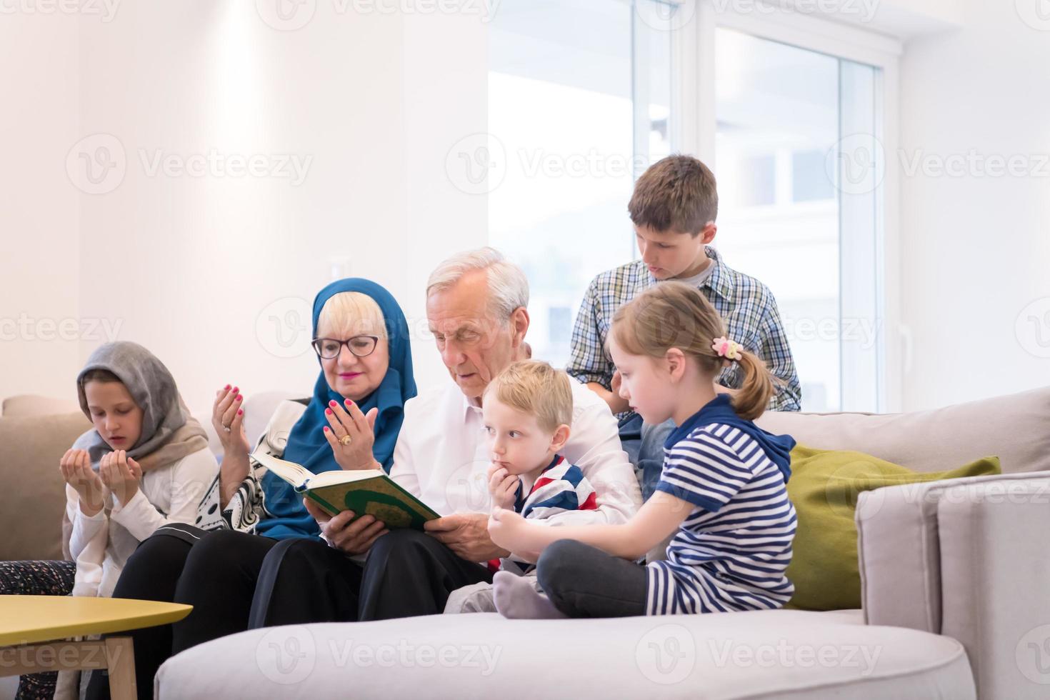 moderne muslimische großeltern mit enkelkindern, die den koran lesen foto