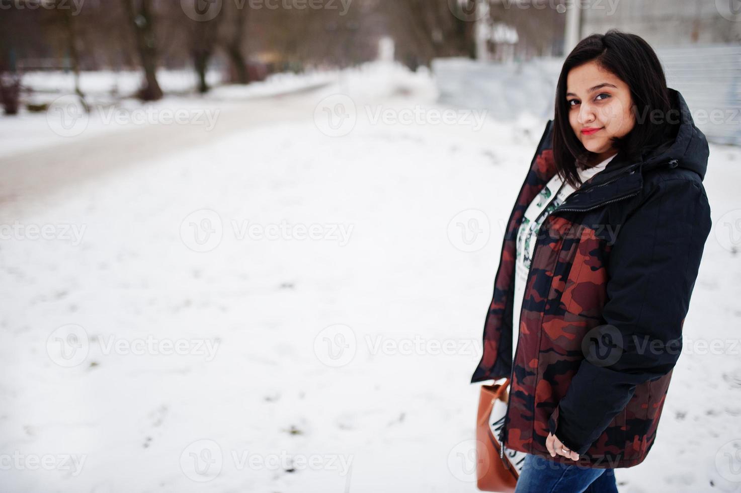 yong asiatische frau trägt jacke mit handtasche am kalten wintertag. foto