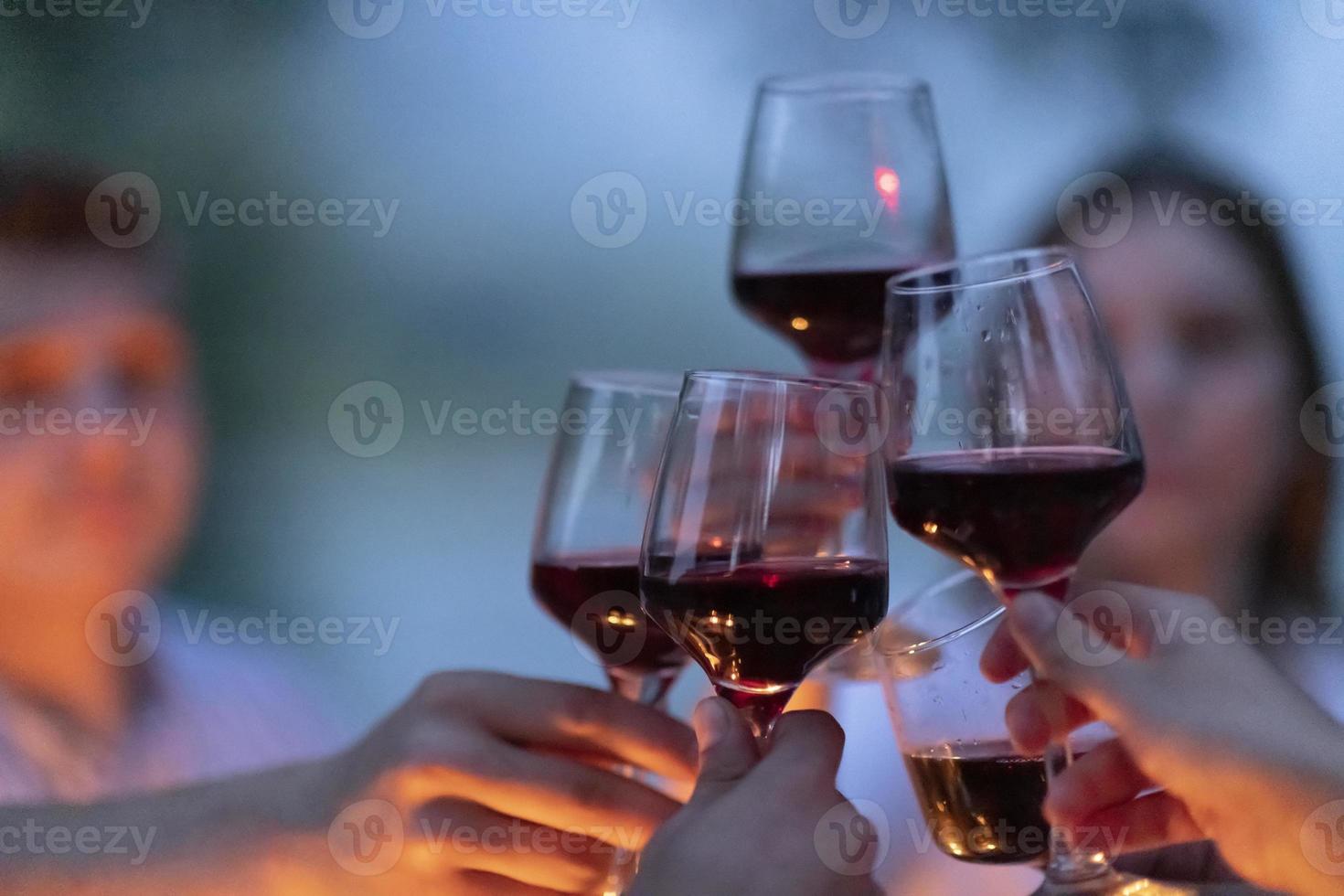 freunde, die rotweinglas toasten, während sie ein französisches picknick-abendessen im freien haben foto