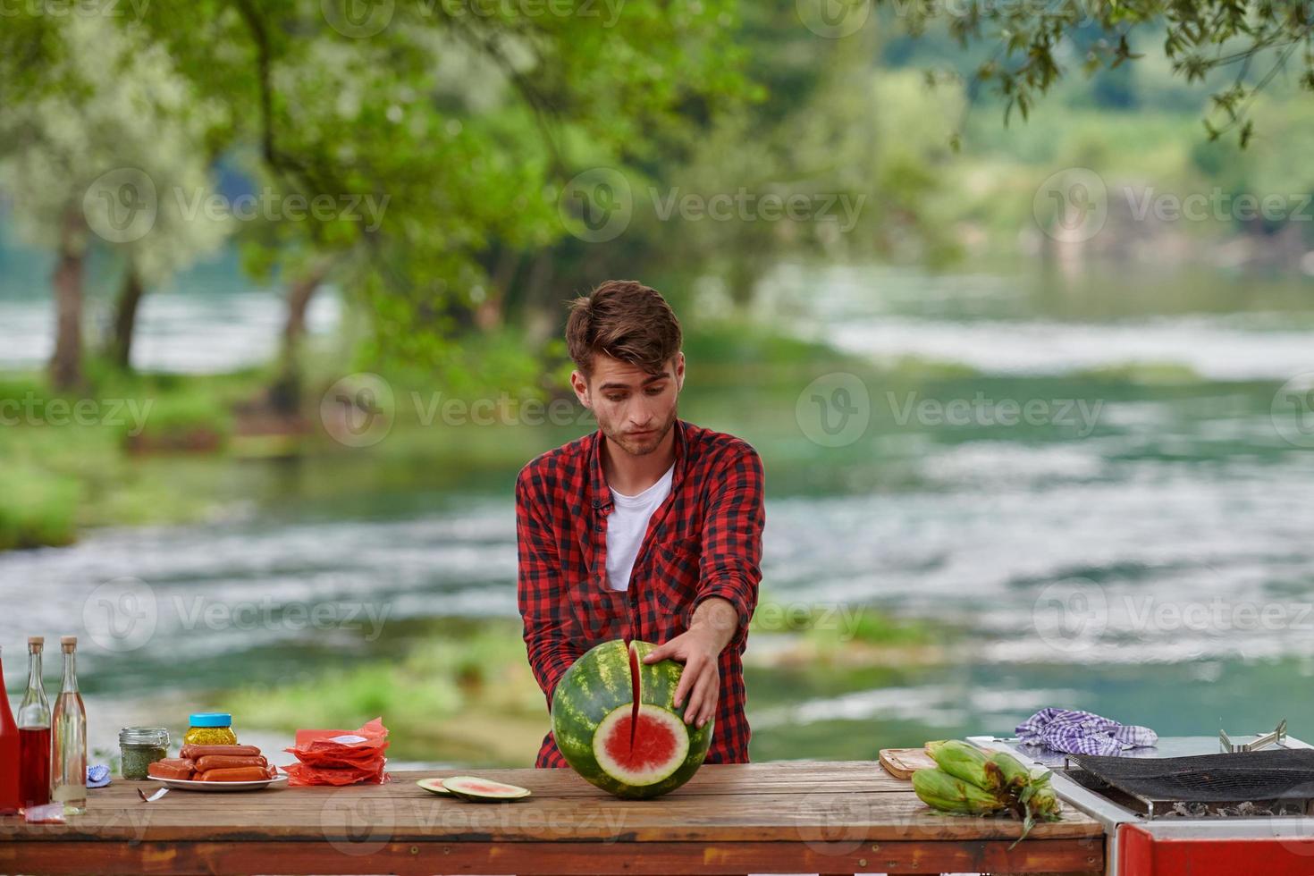 Mann schneidet saftige Wassermelone während einer französischen Dinnerparty im Freien foto