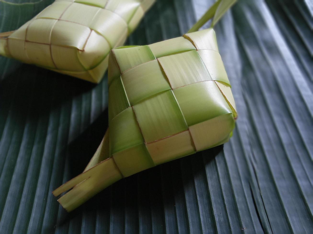 Ketupat oder Reisknödel ist eine lokale Delikatesse während der festlichen Jahreszeit. Ketupats, eine natürliche Reishülle aus jungen Kokosblättern zum Kochen von Reis isoliert auf weißem Hintergrund foto