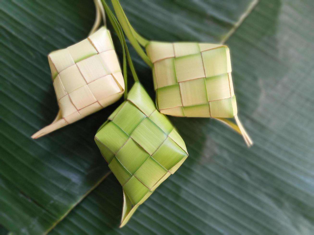 ketupat ist in indonesien eine art, reis zu kochen, indem reis in ein kokosnussblatt gesteckt wird, das wie ein diamant geformt ist. dann gedämpft. sehr berühmt in indonesien. erscheint normalerweise auf eid al-fitr foto