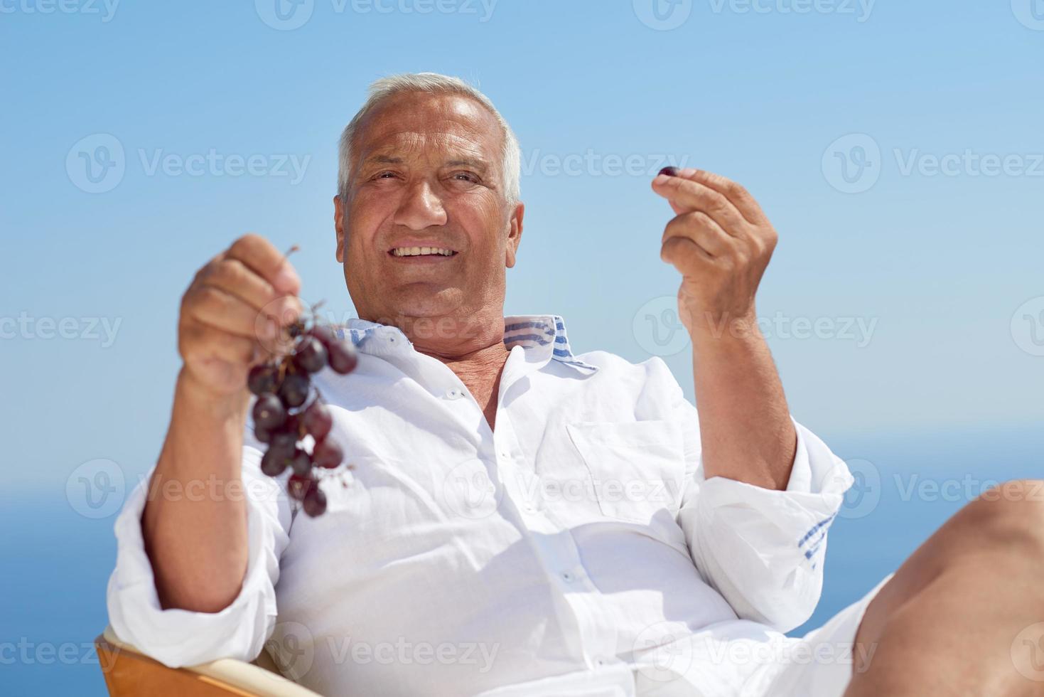 älterer Mann, der draußen sitzt foto