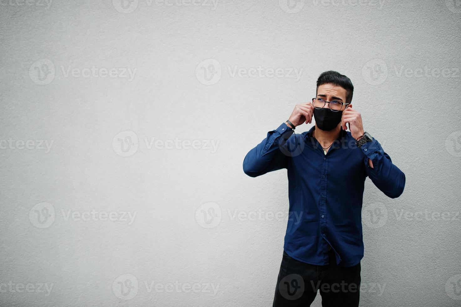 Unternehmer aus dem Nahen Osten tragen eine schwarze Gesichtsmaske und eine Brille vor einer weißen Wand. neues normales Leben nach der Coronavirus-Pandemie. foto