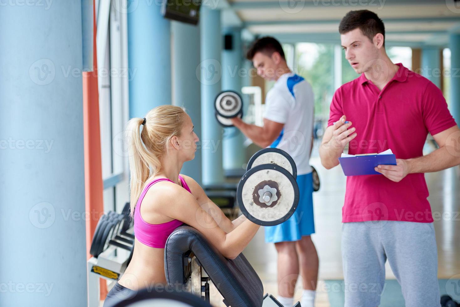 junge sportliche frau mit trainer übung gewichte heben foto