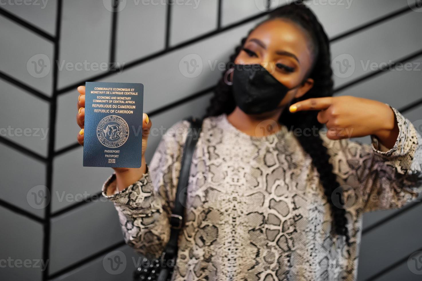 afrikanische frau mit schwarzer gesichtsmaske zeigt kamerun-pass in der hand. coronavirus in afrika land, grenzschließung und quarantäne, virusausbruchskonzept. foto