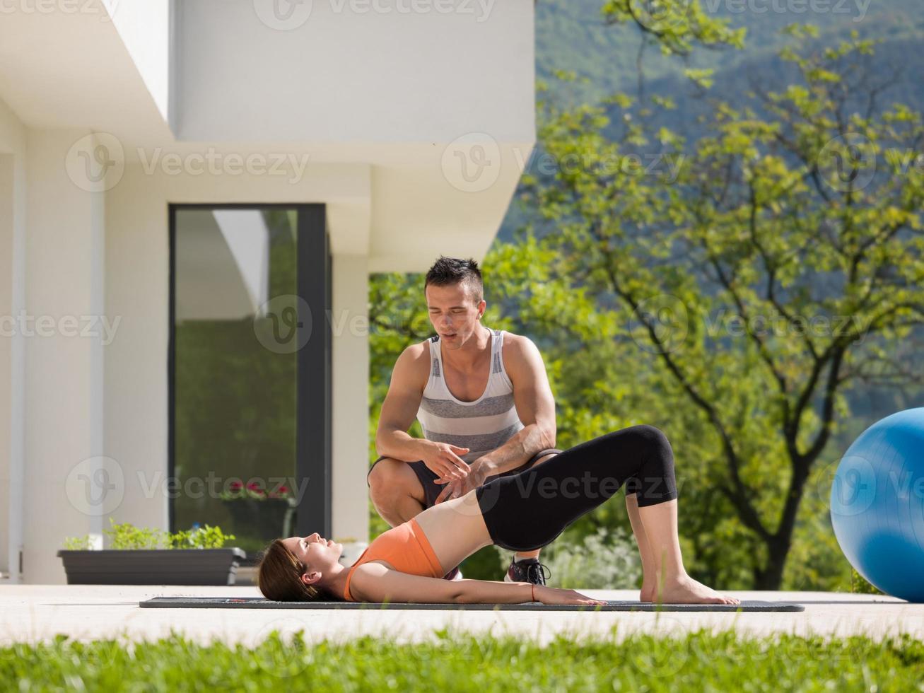 Frau mit persönlichem Trainer, die morgendliche Yoga-Übungen macht foto