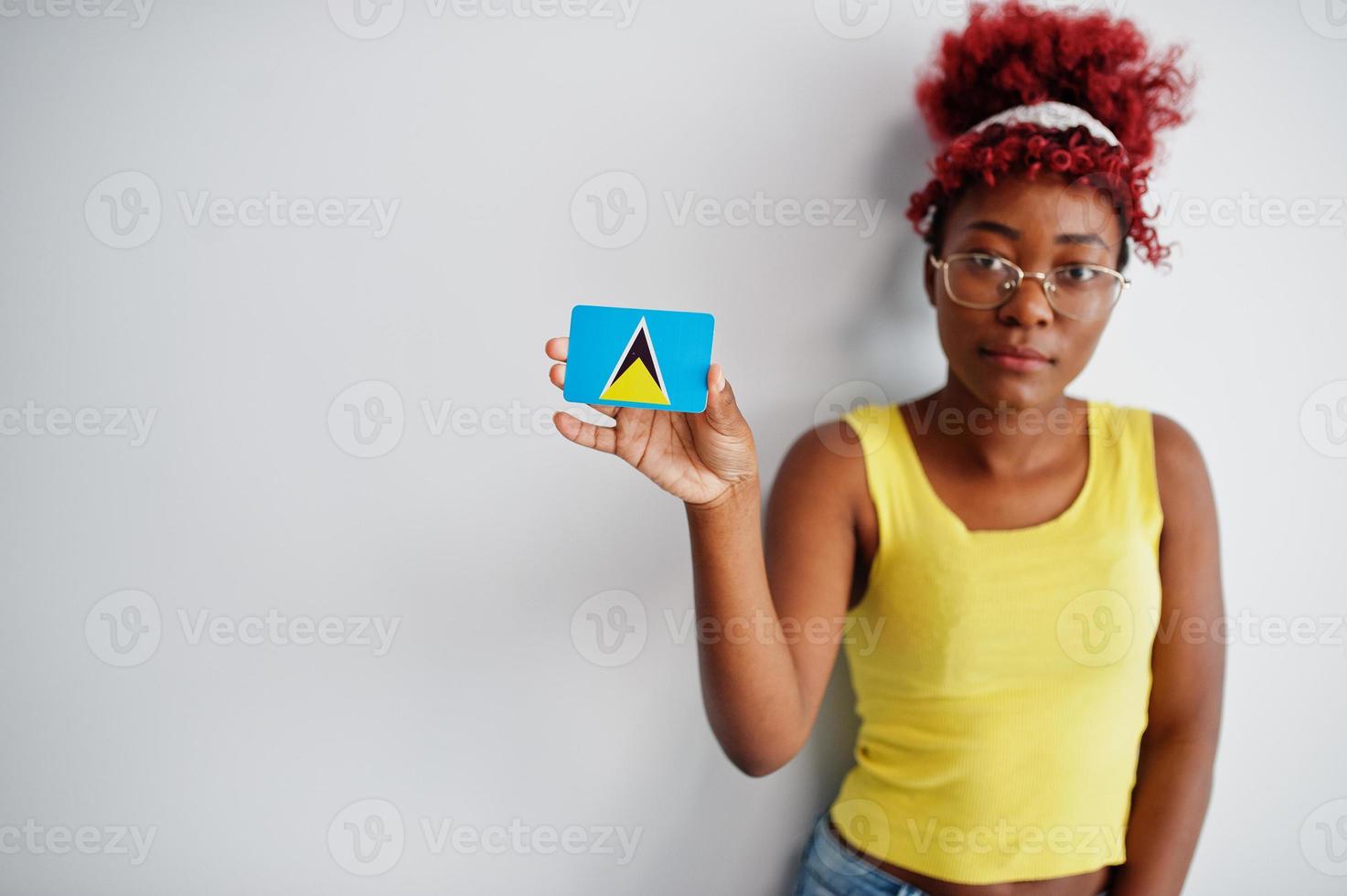 afroamerikanerin mit afrohaar, trägt gelbes unterhemd und brille, hält st. lucia flagge isoliert auf weißem hintergrund. foto