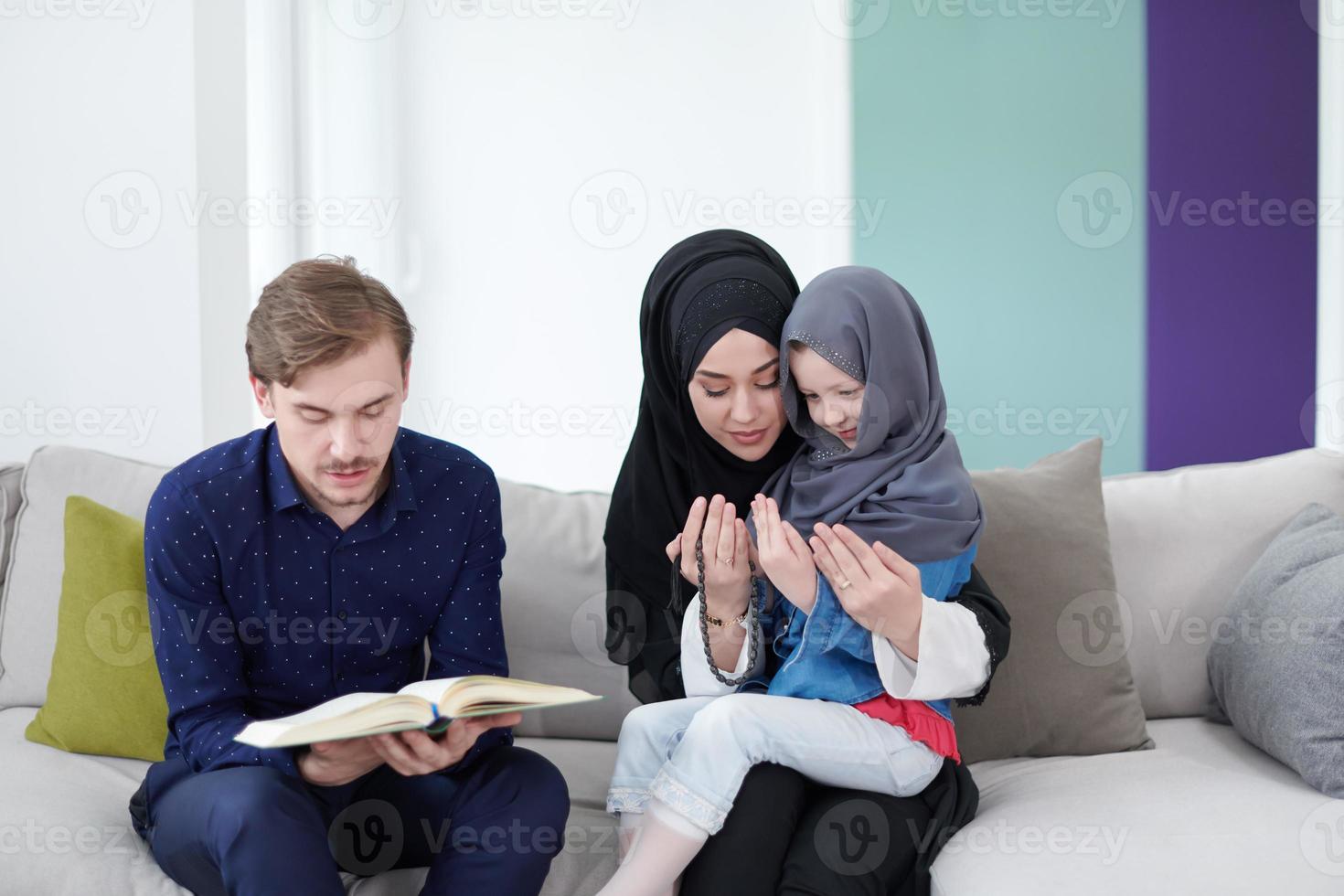 muslimische familie, die koran liest und zu hause betet foto