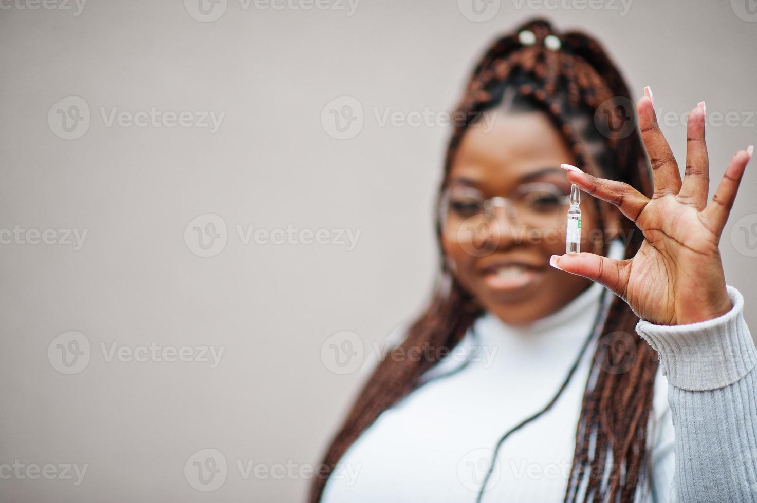 Afroamerikanerin mit Brille zeigt Impfstoff. foto