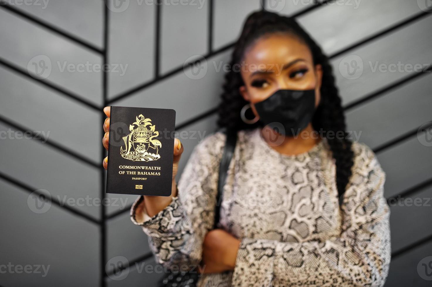 afroamerikanerin mit schwarzer gesichtsmaske zeigt bahamas-pass in der hand. coronavirus im amerikanischen land, grenzschließung und quarantäne, virusausbruchskonzept. foto