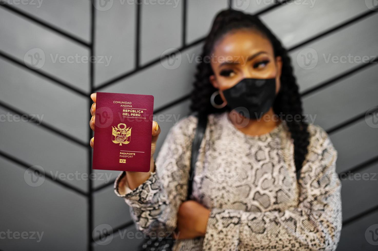 afroamerikanerin mit schwarzer gesichtsmaske zeigt peru-pass in der hand. coronavirus im amerikanischen land, grenzschließung und quarantäne, virusausbruchskonzept. foto