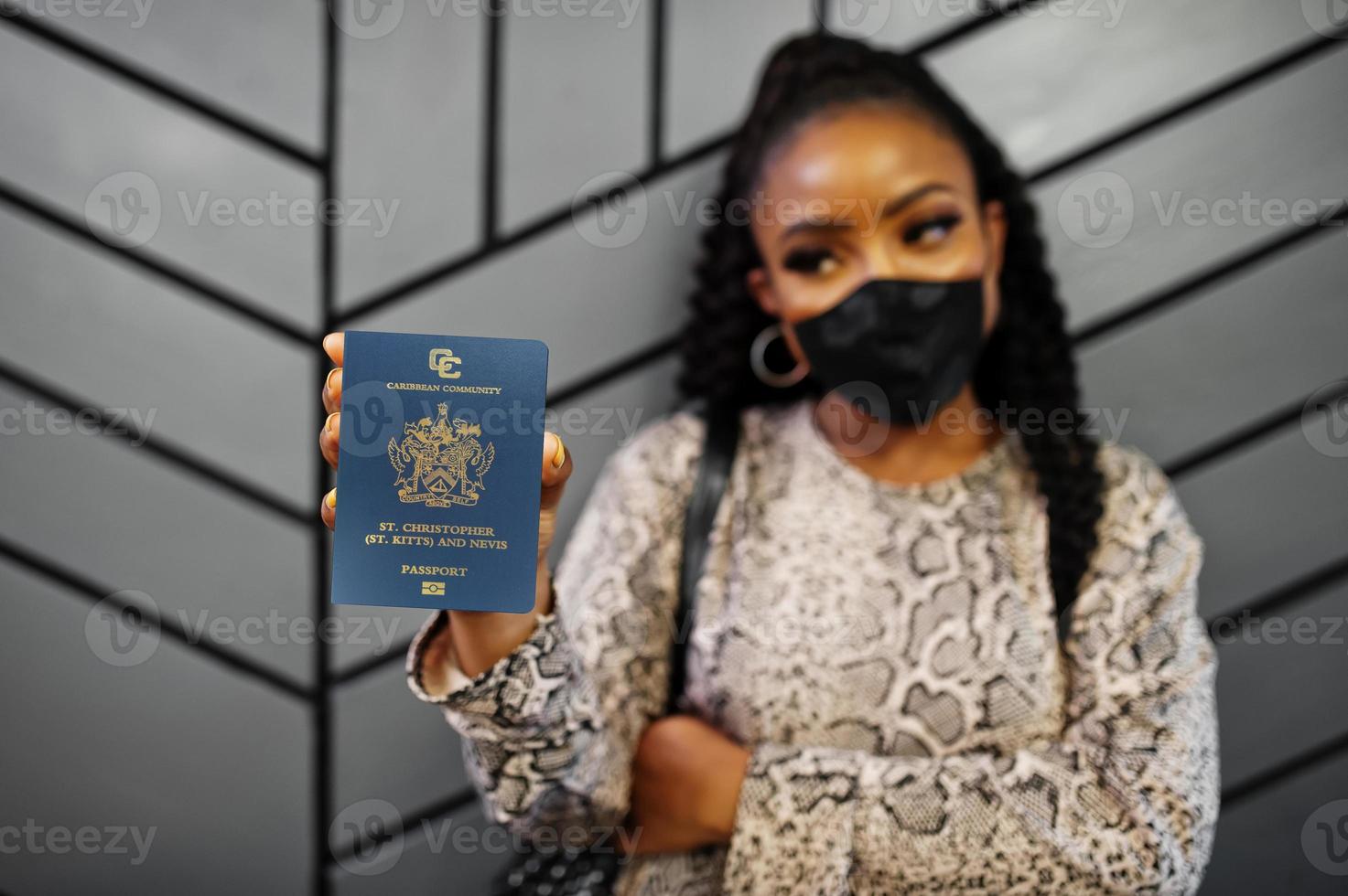 Afroamerikanerin mit schwarzer Gesichtsmaske zeigt den Pass von St. Kitts und Nevis in der Hand. coronavirus im amerikanischen land, grenzschließung und quarantäne, virusausbruchskonzept. foto