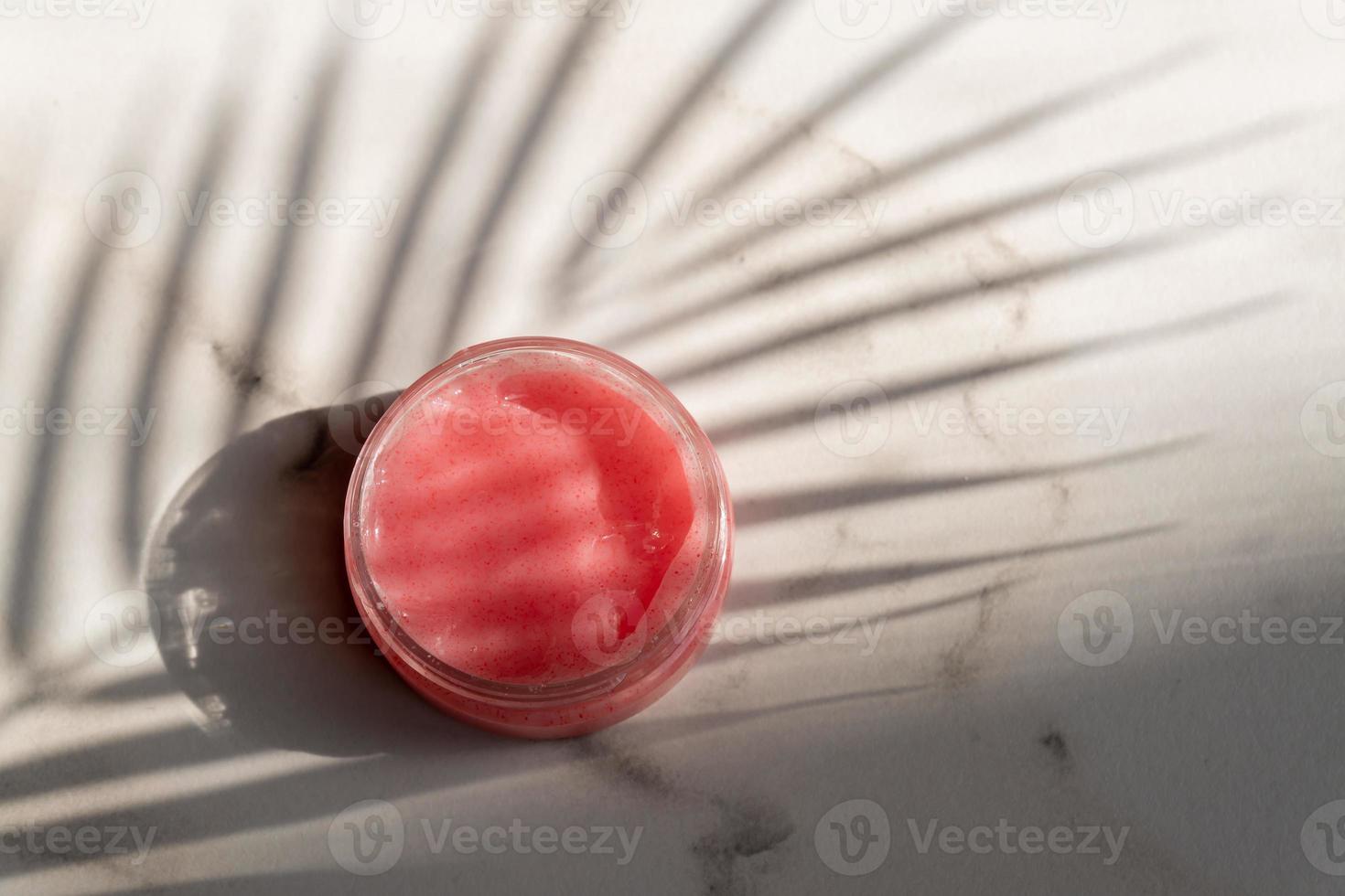 kosmetische gläser aus rosa schrubben mit blattschatten auf weißem marmorhintergrund. Naturkosmetik mit pflanzlichen Inhaltsstoffen. Schönheitsprodukt, Gesundheits- und Hautpflegekonzept foto