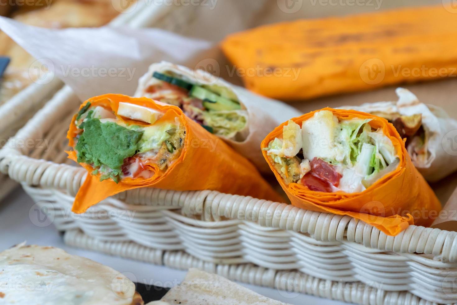 Sandwich in flachem Orangenbrot gerollt. Veganes Sandwich in Lavash mit Gemüse auf dem Streetfood-Markt foto