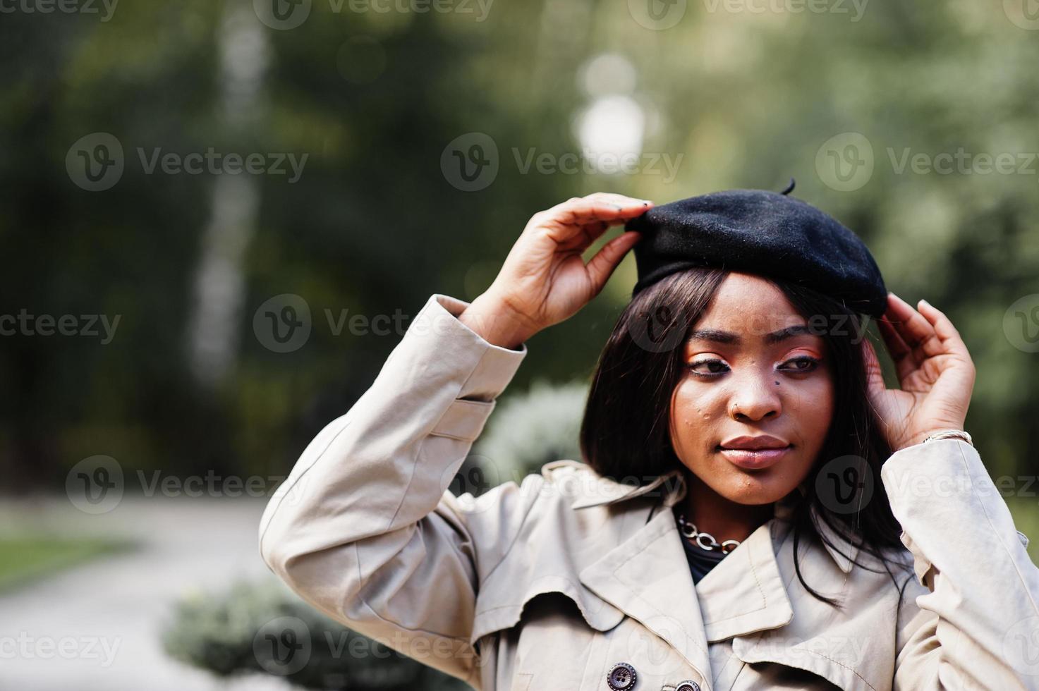 Nahaufnahme Porträt einer modischen afroamerikanischen Frau, die Baskenmütze und Mantel trägt und im Freien posiert. foto