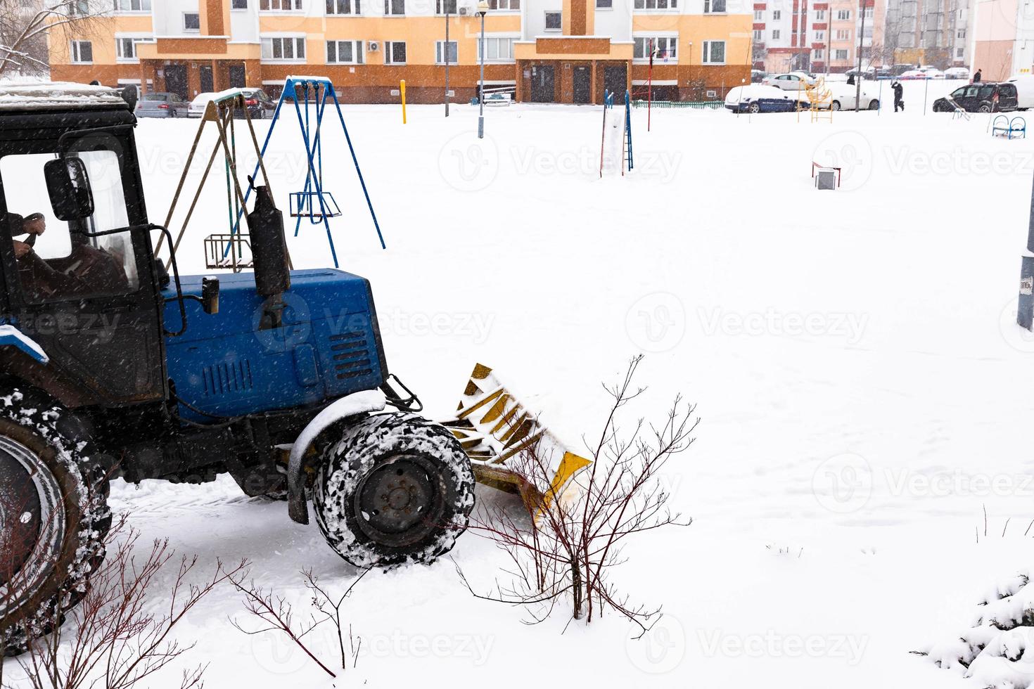 Der Traktor räumt die Straße im Winter bei Schneefall vom Schnee. foto