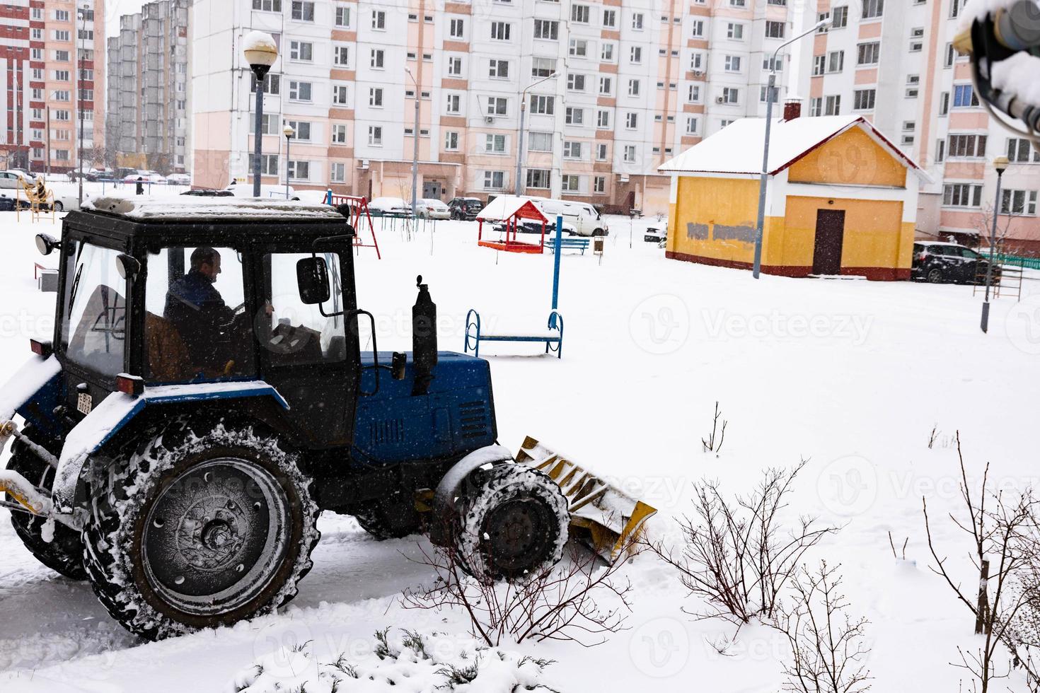 Der Traktor räumt die Straße im Winter bei Schneefall vom Schnee. foto