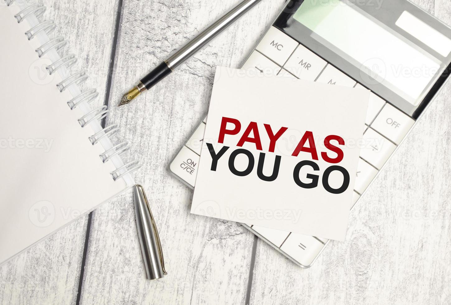 Pay-as-you-go-Wort auf weißer Papierkarte und Taschenrechner foto