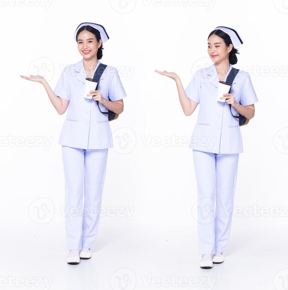 in voller länge 30er 20er jahre asiatische frau krankenschwester krankenhaus, zeigt leere handfläche, trägt formelle einheitliche hosenschuhe. Lächeln Krankenhaus weiblich tragen Rucksack Kaffeetasse Internet-Telefon auf weißem Hintergrund isoliert foto