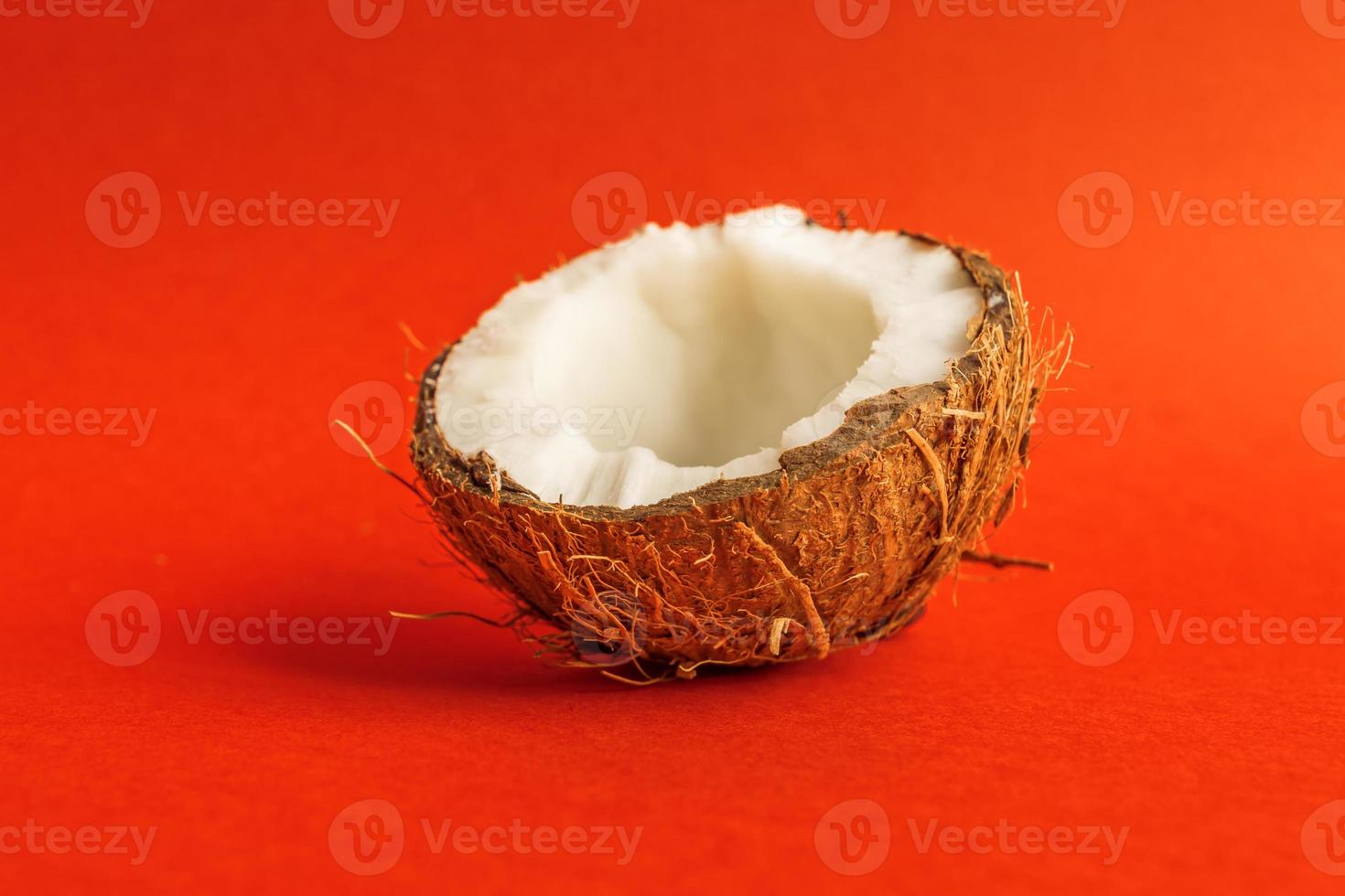 Hälfte der frischen rohen Kokosnuss auf rotem Hintergrund. foto