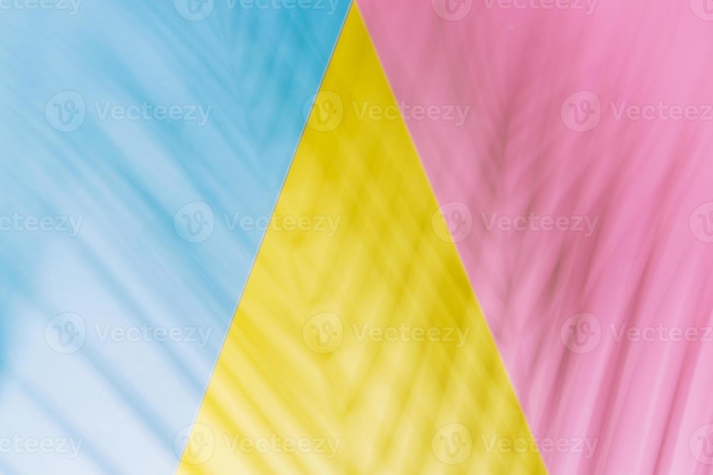 Schatten von Palmblättern auf geometrischem Hintergrund in gelben, rosa und blauen Farben. flacher Lay-Stil. foto