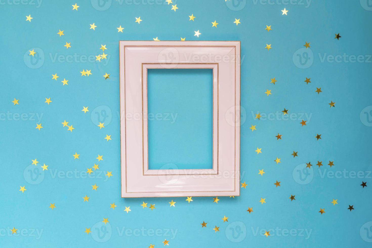 rosa Fotorahmen auf blauem Hintergrund mit verstreuten goldenen Sternen. kreatives Modell. foto