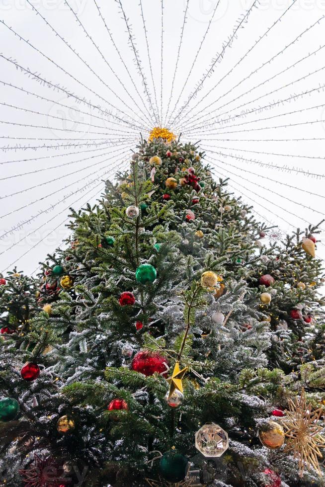 unteransicht der weihnachtsbaumdekoration mit spielzeug und girlanden. festliche Dekoration der Stadt während der Winterferien. foto