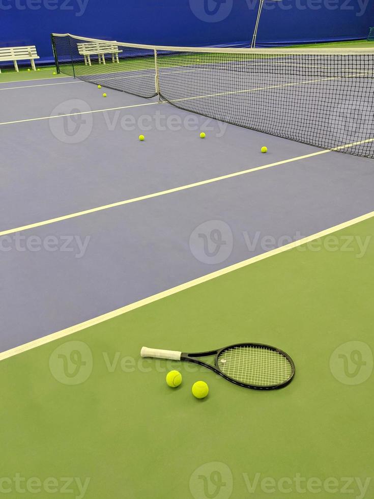 Nahaufnahme von Tennisschläger und zwei Bällen auf dem Tennisplatz mit grünem Sand foto