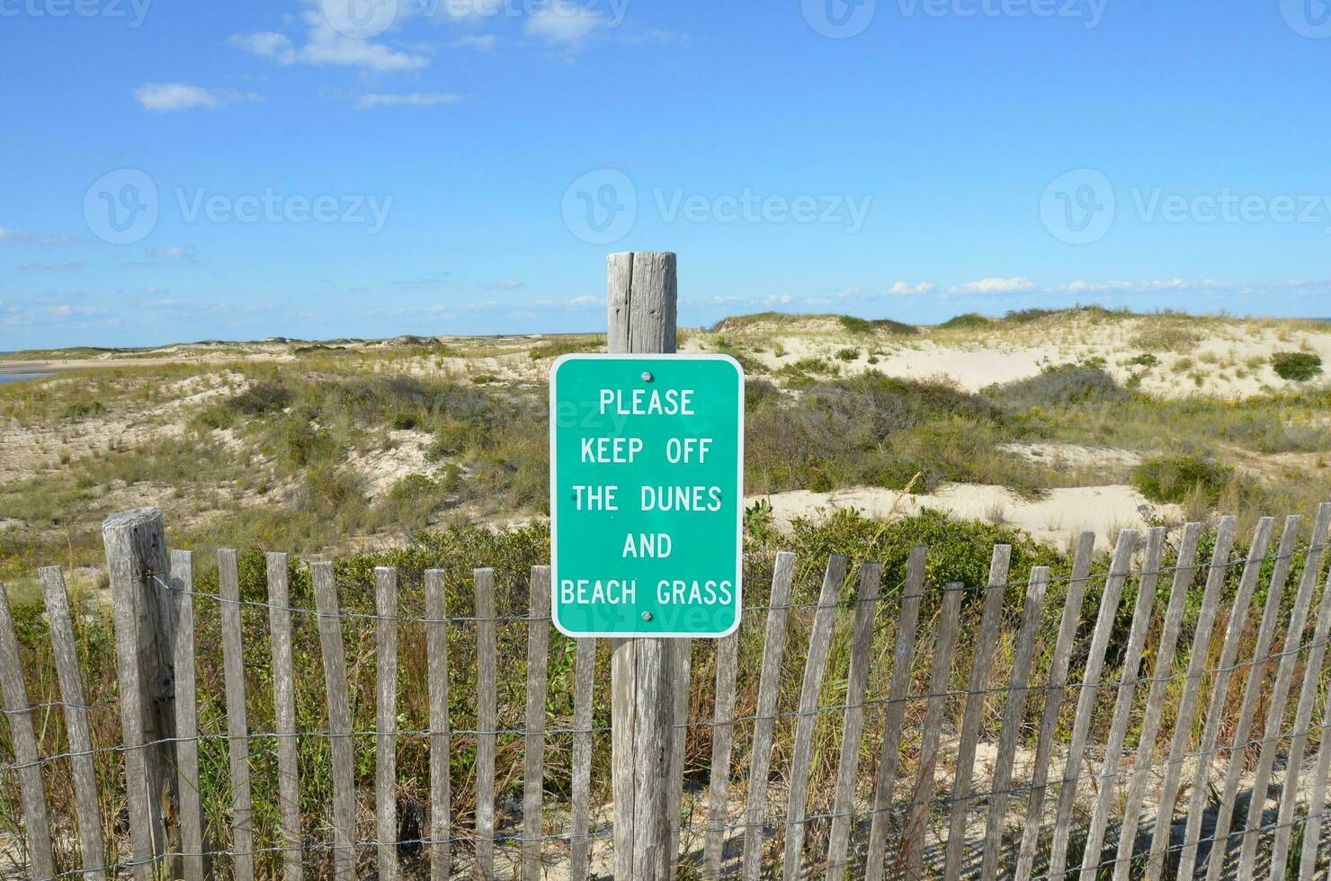 Holzzaun und Sanddünen am Strand mit Bitte-aus-Schild foto